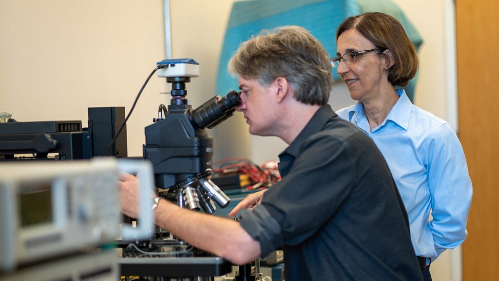 Technologists using microscope in lab