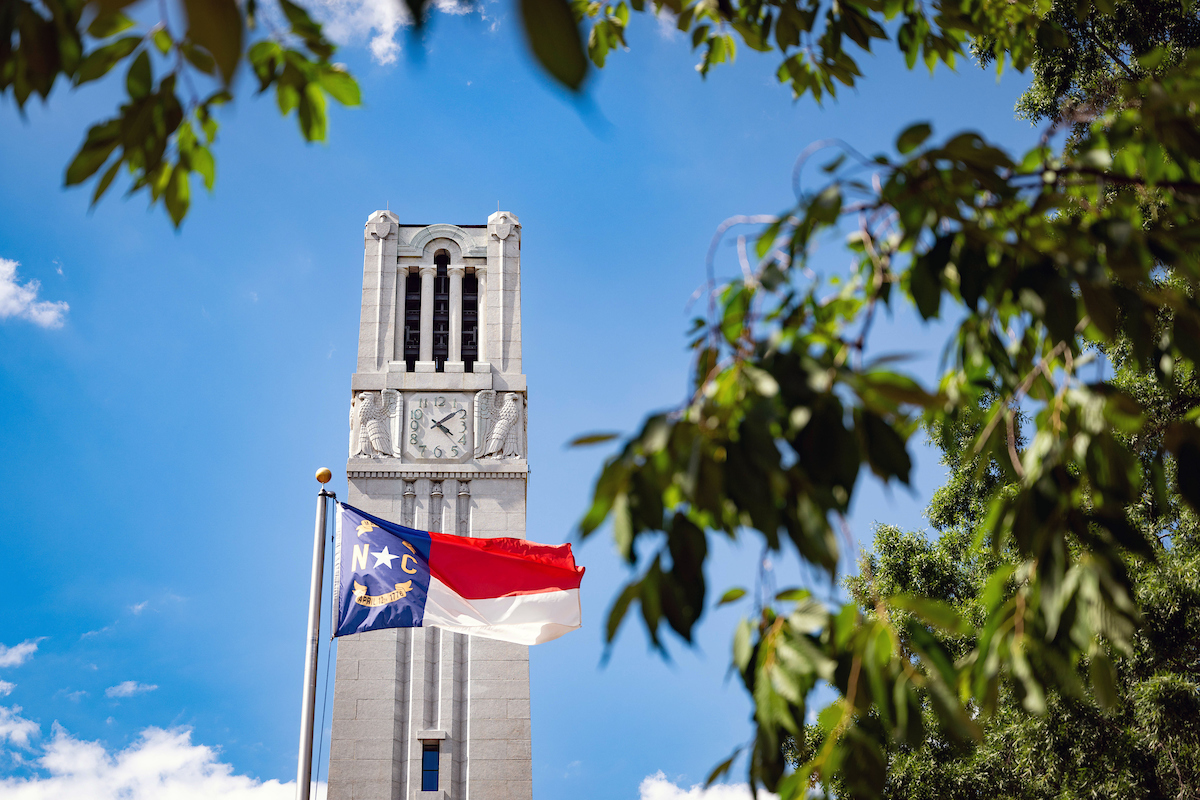 University belltower with state flag in foreground