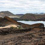A photo of the landscape on the Galapagos Islands. Hills are made up of volcanic rock and are interspersed with small bodies of water.