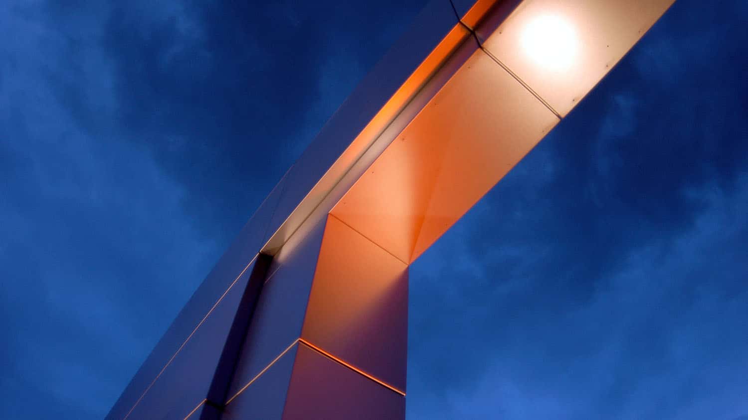 angular metal arch silhouetted against a cloudy sky
