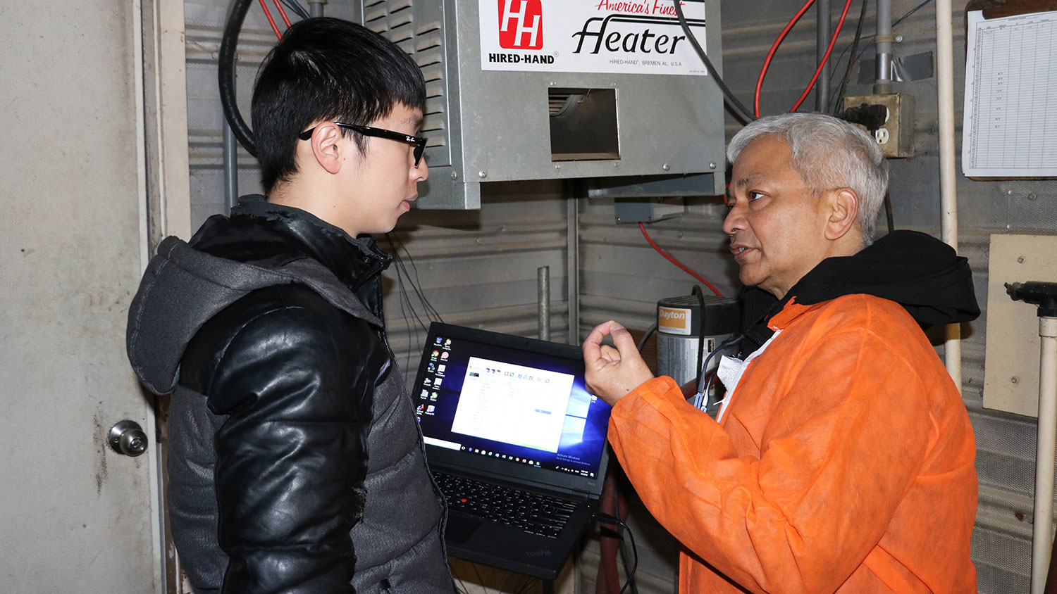 Sanjay Shah discusses temperature conditions in a swine nursery with graduate student Li Yu to evaluate the effectiveness of a solar powered heating system.