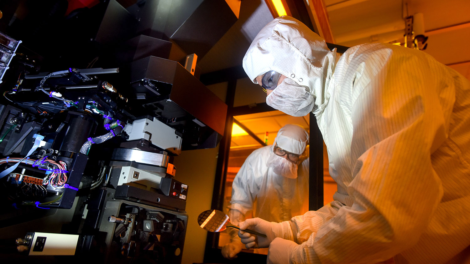 Researchers in full coverage lab gear work on nanofabrication.