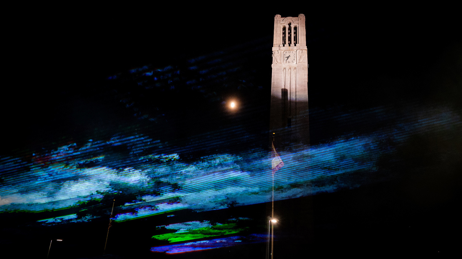 Laser images are projected across NC State's Bell Tower.