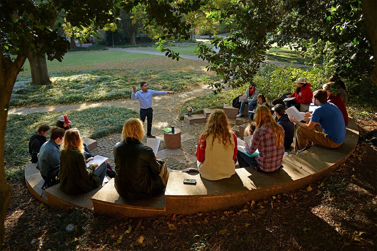 A professor teaches class in the outdoor classroom outside Tompkins Hall.