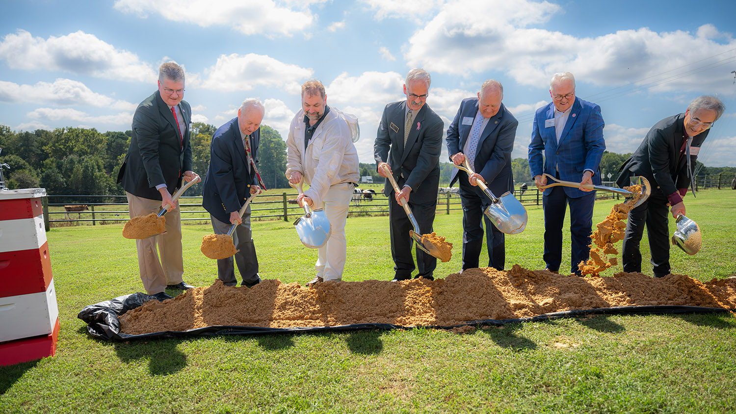 a group of men hold shovels over dirt for a groundbreaking ceremony