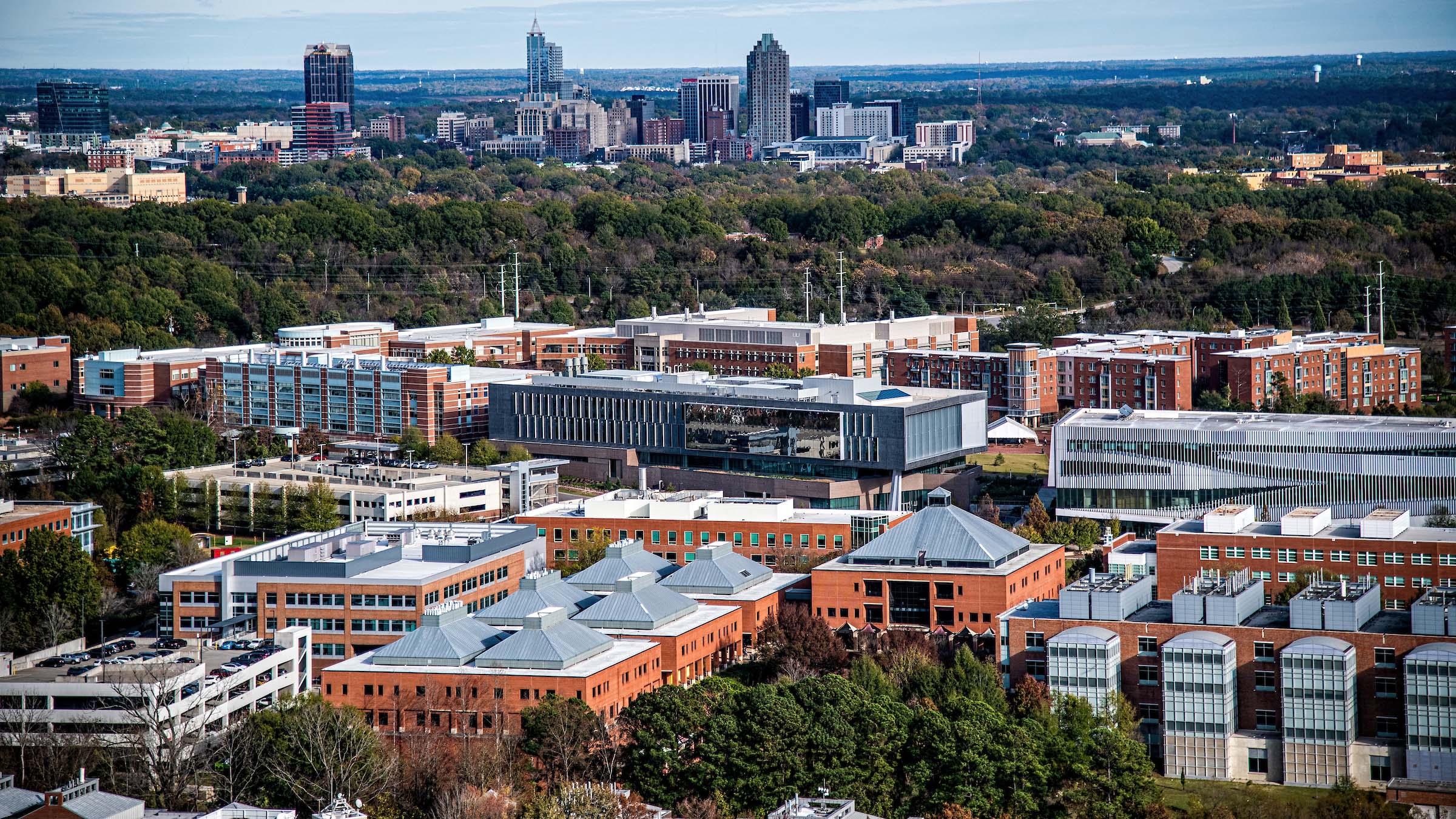 An aerial photo of NC State's Centennial Campus, overlooking the downtown Raleigh skyscape.