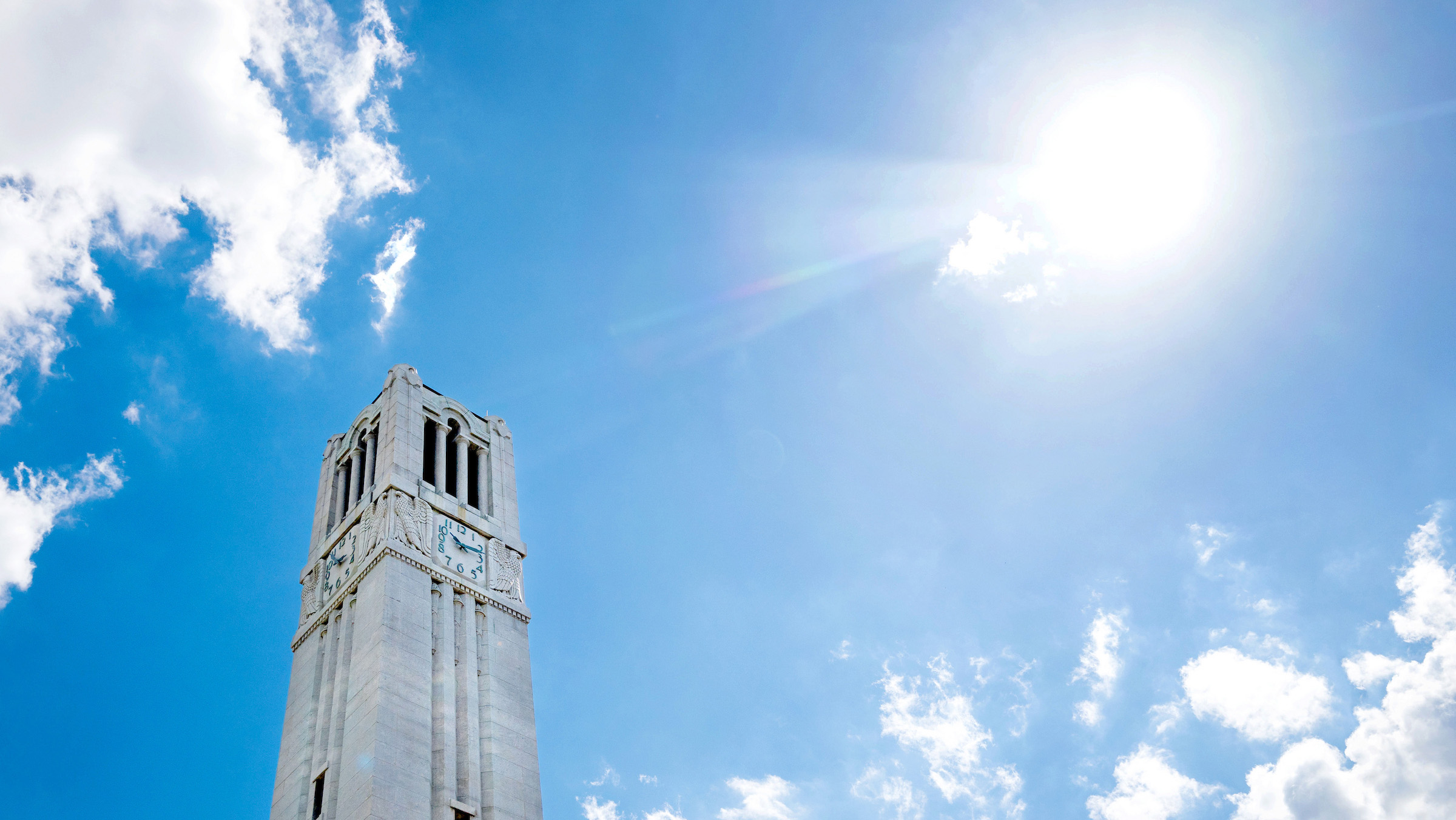 NC State's Memorial Belltower stands in front of a clear summer sky.