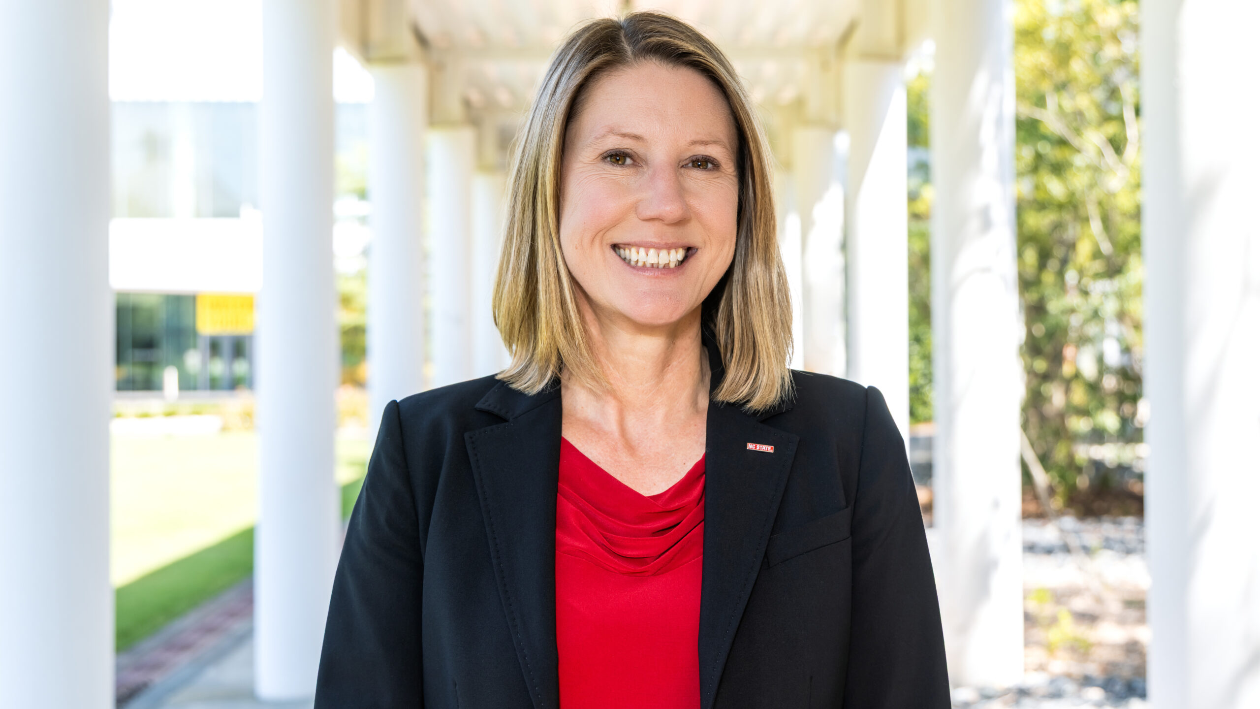 A portrait-style photograph of Vice Chancellor Krista Walton standing underneath the portico between Hunt Library and the Wilson College of Textiles